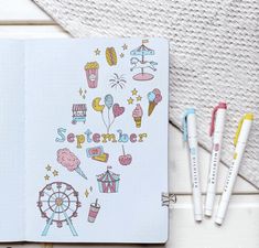 an open notebook sitting on top of a table next to markers