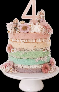 a multi layer cake with flowers and fairy figurines on top is shown in front of the number four