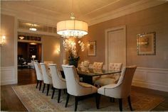 a dining room table with white chairs and a chandelier