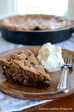 a piece of pie on a plate next to a fork and ice cream dish with a skillet in the background