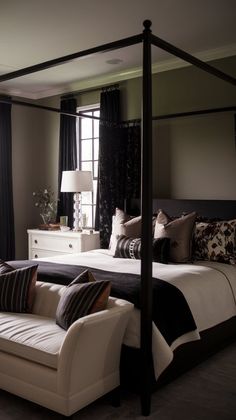 a bedroom with a four poster bed, white couch and black drapes on the windows