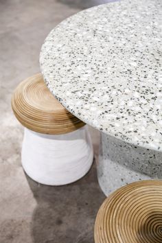 a round table with white sprinkles on it and two wooden stools next to it