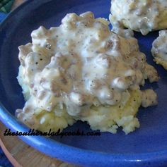 a blue plate topped with potatoes covered in gravy