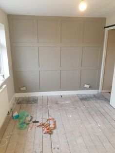 an empty room with wood flooring and walls painted gray, including paint rollers on the floor