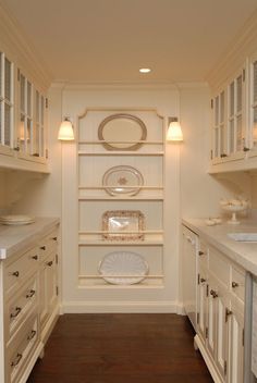 a kitchen with white cabinets and plates on the shelves