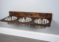 three stainless steel bowls are mounted on a wooden plaque that says, rusty bella max