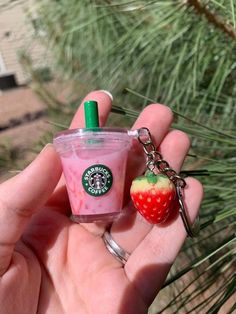 someone is holding a starbucks drink and a strawberry keychain