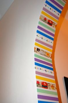 the wall is decorated with colorful strips of paper and tape on it's edge