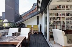 an outdoor deck with chairs, tables and bookshelves on the side of it