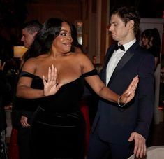 a man in a tuxedo standing next to a woman in a black dress