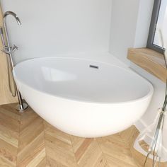 a white bath tub sitting on top of a wooden floor