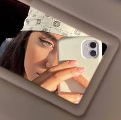 a woman taking a selfie in the mirror with her cell phone while wearing a bandana