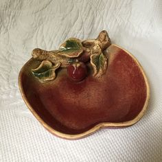 a ceramic dish with cherries in the shape of an apple on a white background