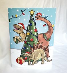 a christmas card with dinosaurs around a tree