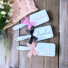 three personalized wooden spoons with pink bows on them next to a bouquet of flowers