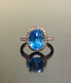 DeKara Designs Collection Our latest design!  An elegant and lustrous Blue Topaz surrounded by beautiful diamonds in a halo setting.Metal- 18K Rose Gold, .750.Stones- Center Features a Oval Fiery Blue Topaz, 11 MM Long, 9 MM Wide, 44 Round Diamonds, G-H Color VS2-SI1 Clarity, 0.35 Carats.Latest of my creations.  A beautiful 18K Rose Gold Blue Topaz Halo Diamond Ring.  The Amethyst is professionally prong set in between 4 double prongs.  There are 10 pave set round diamonds on each side of the sh Luxury Blue Topaz Halo Ring, Blue Bridal Jewelry With Diamond Accents In Cubic Zirconia, Blue Topaz Ring Brilliant Cut For Promise, Blue Cubic Zirconia Wedding Ring With Halo Setting, Dazzling Blue Diamond Promise Ring, Blue Brilliant Cut Topaz Ring For Anniversary, Light Blue Diamond Ring With Accent Stones For Wedding, Light Blue Sapphire Ring With Center Stone For Wedding, Formal Blue Halo Ring With Diamond Accents