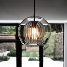 a glass light hanging from a ceiling in a living room next to a large window