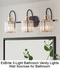 three light bathroom vanity lights with clear glass shades and gold accents on the wall above it