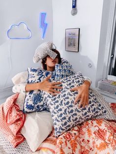 a woman laying on top of a bed covered in pillows