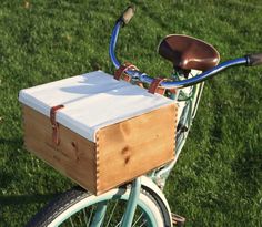 a blue bicycle with a wooden box on the handlebars parked in green grass