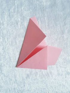 an origami piece is folded in pink paper