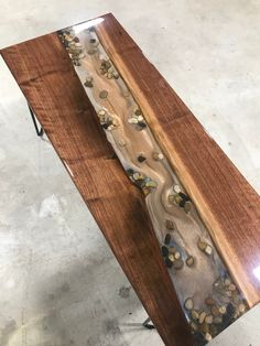 a wooden bench sitting on top of a cement floor next to a metal stand with rocks in it