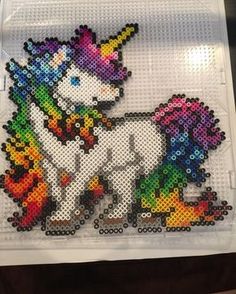 an image of a cross stitch unicorn on a piece of white plastic with rainbows all over it