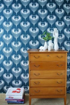 a wooden dresser sitting in front of a wall with a blue and white pattern on it