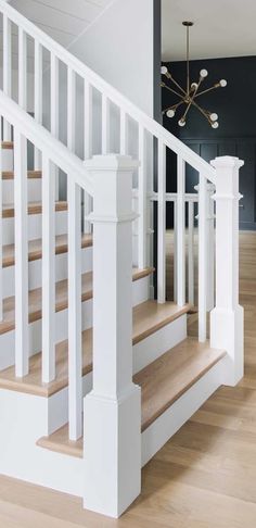 a white staircase with wooden handrails and light wood flooring in a home