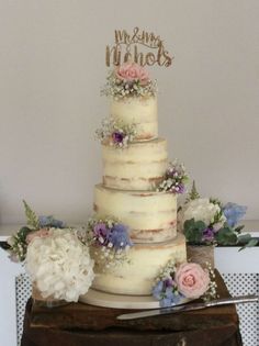 a three tiered wedding cake with flowers on the top is sitting on a table