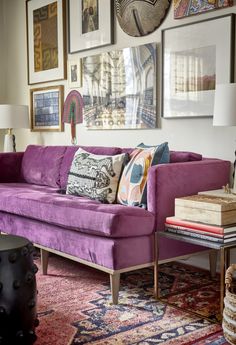 a living room filled with purple couches and pictures on the wall above each sofa