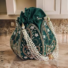 Introducing the Elegant Lotus Potli Bag by Byra, a masterpiece of traditional craftsmanship and contemporary design. This unique embroidered Indian bridal potli bag is an ideal accessory for weddings, engagements, bridesmaid gifts, and anniversary presents. Its intricate detailing and luxurious finish make it a standout piece that exudes elegance and sophistication. Description: Elegant Lotus Potli Bag - Unique Embroidered Indian Bridal Potli for Weddings, Engagements, Bridesmaid & Anniversary G Luxury Zari Work Potli Bag, Luxury Traditional Zari Work Potli Bag, Luxury Gold Embroidered Potli Bag, Luxury Zari Work Evening Bag For Reception, Luxury Embellished Potli Bag For Celebration, Luxury Festive Potli Bag With Tassels, Luxury Traditional Potli Bag For Parties, Luxury Elegant Potli Bag With Mirror Work, Luxury Elegant Potli Bag For Festive Occasions