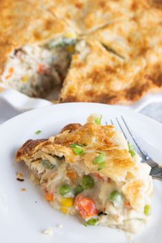 a slice of vegetable pie on a white plate with a fork next to the pie