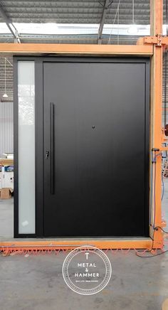 an industrial steel door being installed in a warehouse with orange scaffolding around it