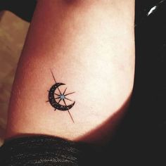 a small compass tattoo on the side of a woman's thigh, with an arrow in the center