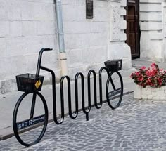 there is a bike rack on the side of the street with flowers in front of it