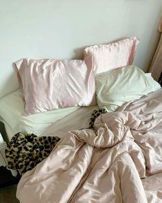 an unmade bed with pink sheets and leopard print pillowcases on top of it