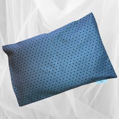 a blue polka dot pillow on a white sheeted background with a tag in the corner