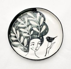 a black and white plate with a woman holding a bird on it's side