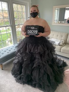 a woman in a black dress wearing a mask and holding a sign that says yes dress up