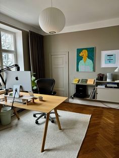 an office area with a desk, chair and computer on top of a rug in front of a window