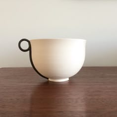 a white bowl sitting on top of a wooden table next to a framed photo and a black handle