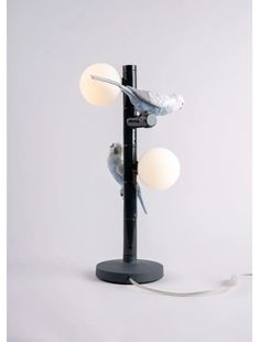 a lamp that is on top of a stand with two birds sitting on the base