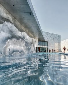 people are walking around an indoor swimming pool