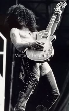 a man with long hair playing an electric guitar in black and white photo by vintage treasures