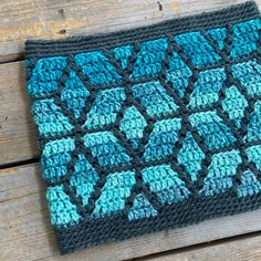 a blue and black crocheted dishcloth sitting on top of a wooden table