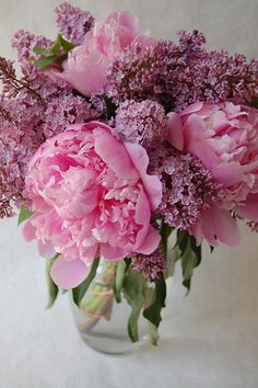 a glass vase filled with pink flowers on top of a white tablecloth covered floor