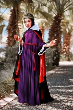 a woman in a purple dress and crown with palm trees behind her is holding out her hand