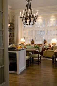 a living room filled with lots of furniture and a chandelier hanging from the ceiling