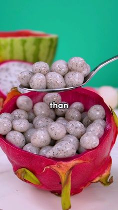 a dragon fruit with white speckles and a spoon full of them sitting on a table